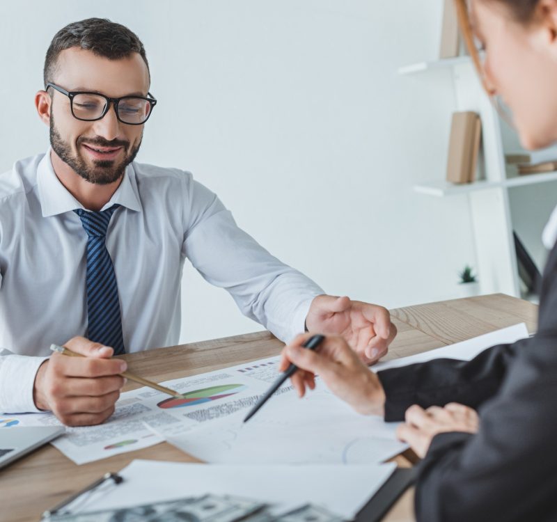 cheerful financiers pointing on documents in office